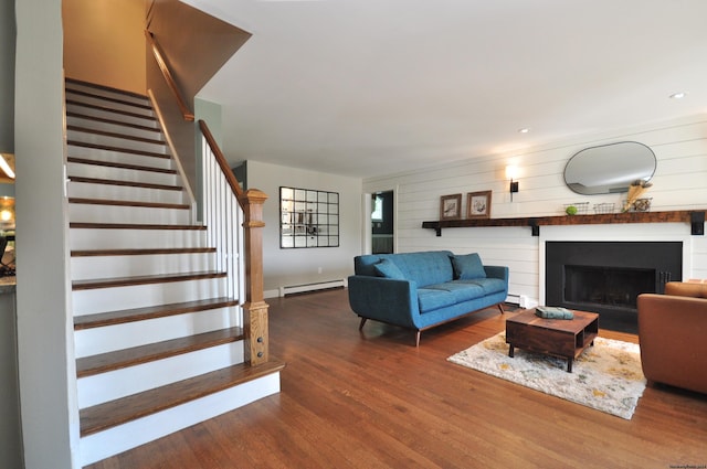 living area featuring a baseboard radiator, a fireplace, stairway, and wood finished floors