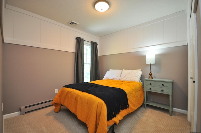 carpeted bedroom with visible vents, a baseboard heating unit, and baseboards