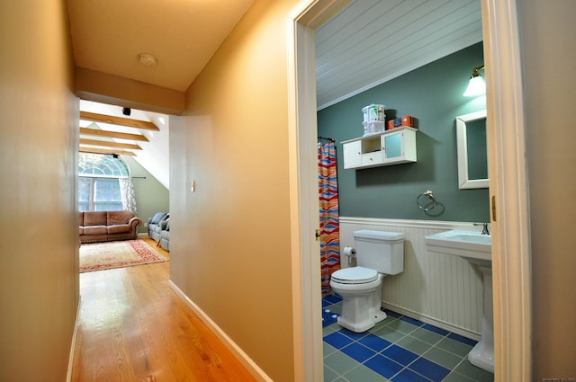 full bath with toilet, vaulted ceiling, wood finished floors, and wainscoting