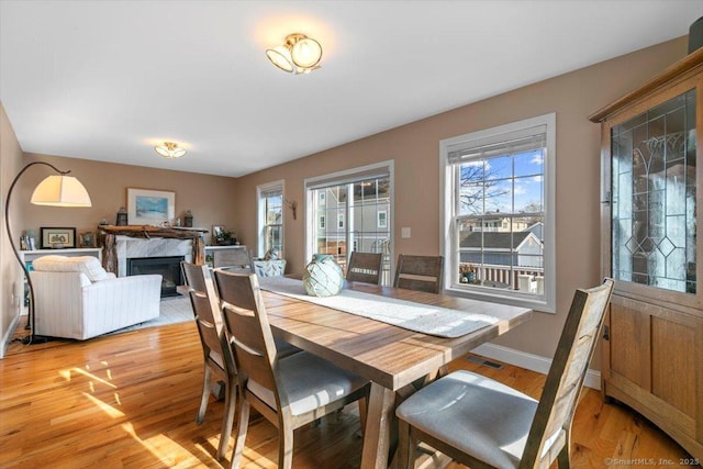 dining area featuring a wealth of natural light, a premium fireplace, and light wood-type flooring