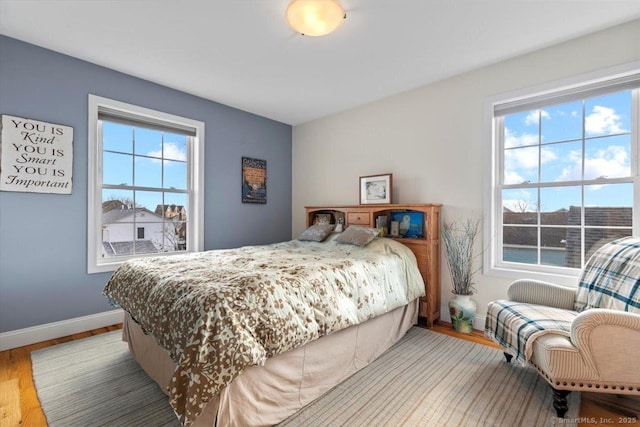 bedroom with multiple windows and hardwood / wood-style flooring