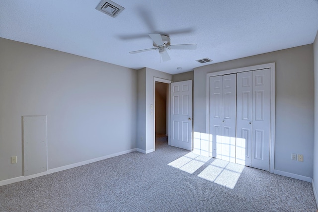 unfurnished bedroom featuring ceiling fan, a closet, light carpet, and a textured ceiling