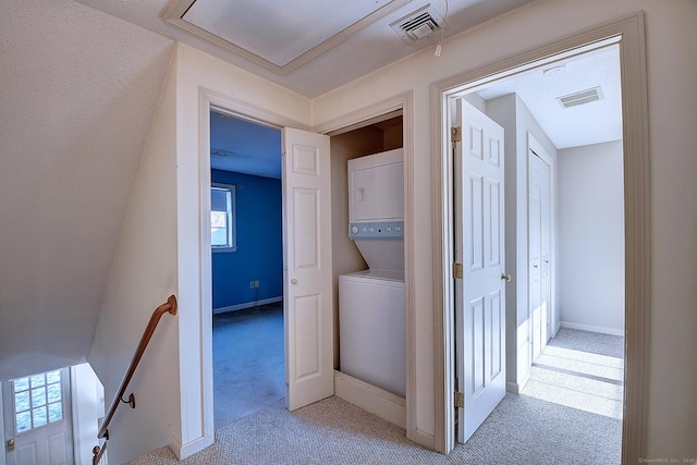 interior space with stacked washing maching and dryer and light carpet