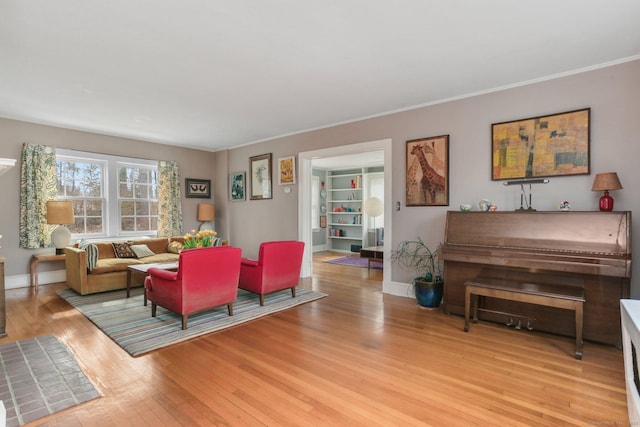 living room with baseboards, crown molding, and light wood finished floors