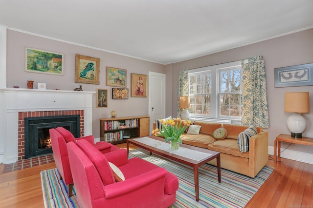 living area featuring ornamental molding, light wood finished floors, a fireplace, and baseboards