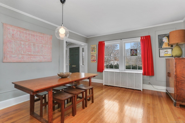 dining space with light wood-type flooring, baseboards, crown molding, and radiator heating unit