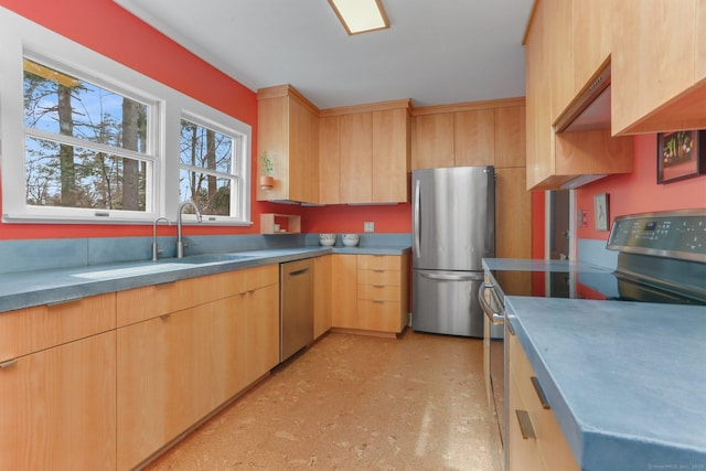 kitchen with appliances with stainless steel finishes, a sink, light floors, and light brown cabinetry