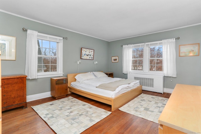 bedroom with light wood-style floors, radiator heating unit, and baseboards