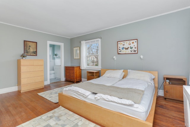 bedroom featuring ornamental molding, ensuite bathroom, baseboards, and wood finished floors