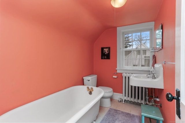 bathroom featuring radiator, a soaking tub, toilet, vaulted ceiling, and tile patterned floors