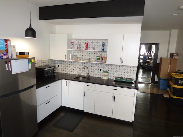 kitchen with sink, white cabinetry, tasteful backsplash, decorative light fixtures, and stainless steel refrigerator