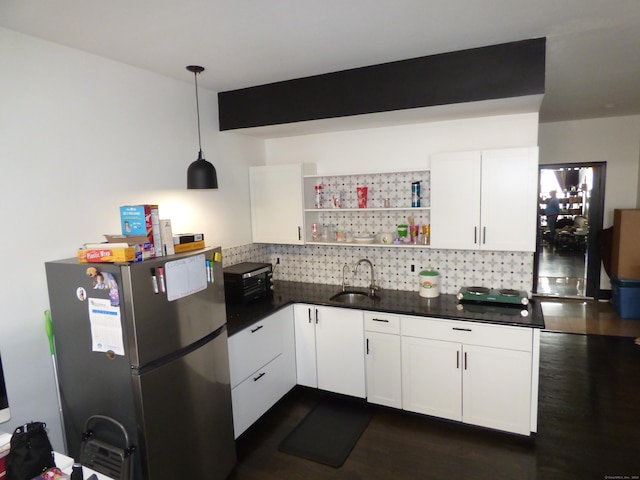 kitchen with white cabinetry, sink, pendant lighting, and stainless steel fridge