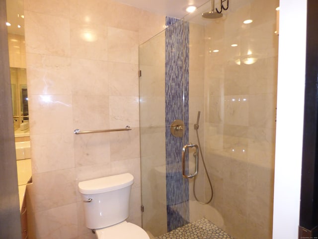 bathroom with tile walls, toilet, and tiled shower