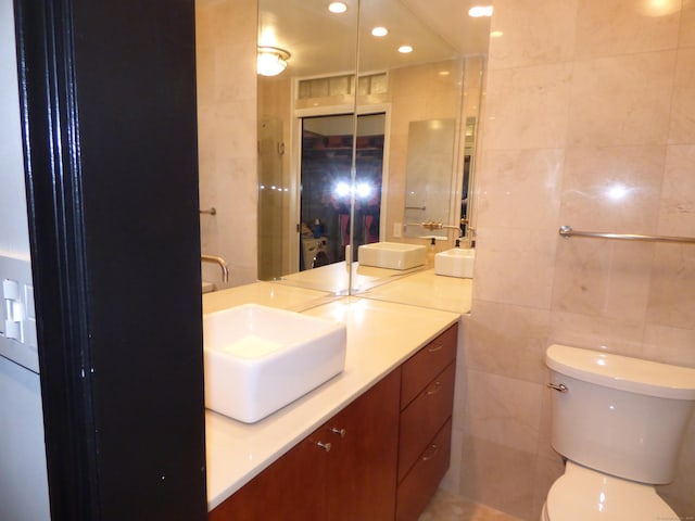 bathroom with tile walls, vanity, and toilet