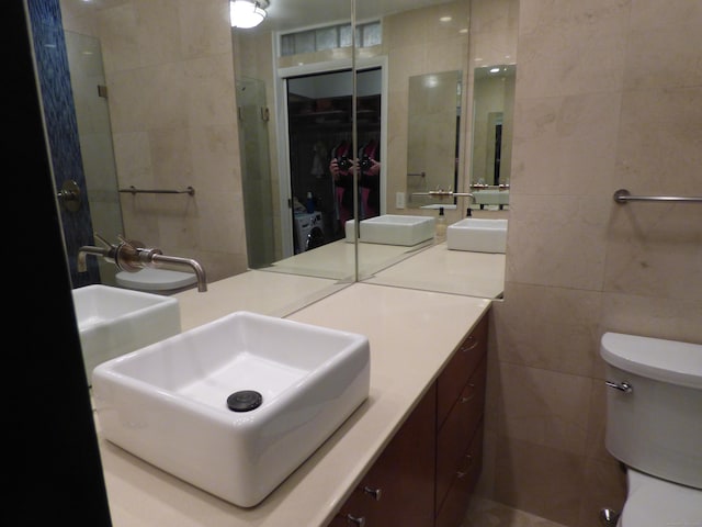 bathroom with vanity, tile walls, and toilet