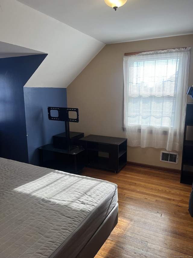 bedroom with wood-type flooring and vaulted ceiling