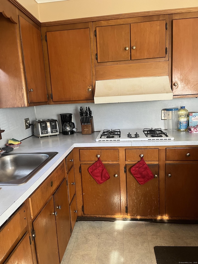 kitchen with white gas stovetop, sink, and light tile patterned floors