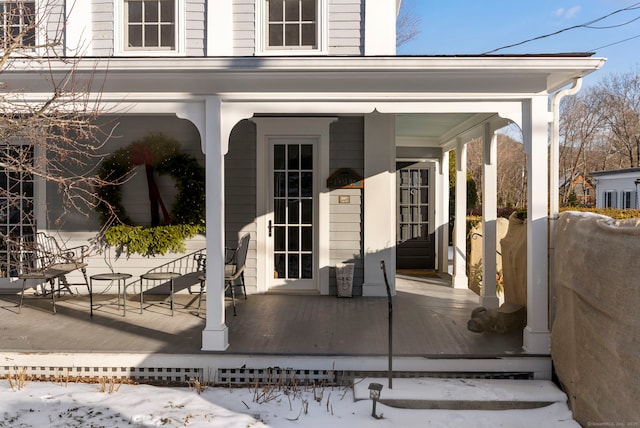 snow covered property entrance with covered porch