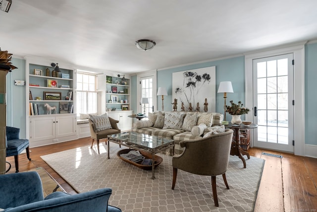 living room featuring ornamental molding, a wealth of natural light, and light hardwood / wood-style flooring