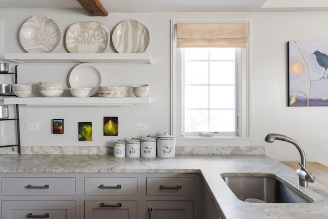 bar with sink, gray cabinetry, and light stone counters