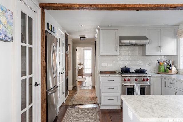 4 Main St, Salisbury, CT 06068 - kitchen featuring wall chimney exhaust hood, stainless steel appliances, decorative backsplash, dark wood-type flooring, and light stone counters