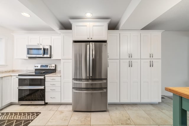 kitchen featuring white cabinetry, stainless steel appliances, light tile patterned flooring, and light stone counters