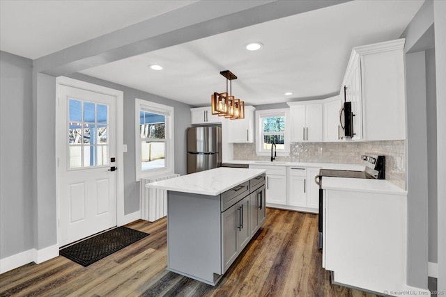 kitchen featuring stainless steel appliances, decorative light fixtures, a center island, and white cabinets