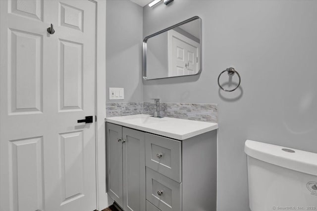 bathroom featuring tasteful backsplash, vanity, and toilet