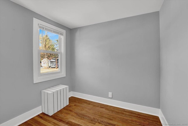 spare room featuring hardwood / wood-style floors and radiator heating unit