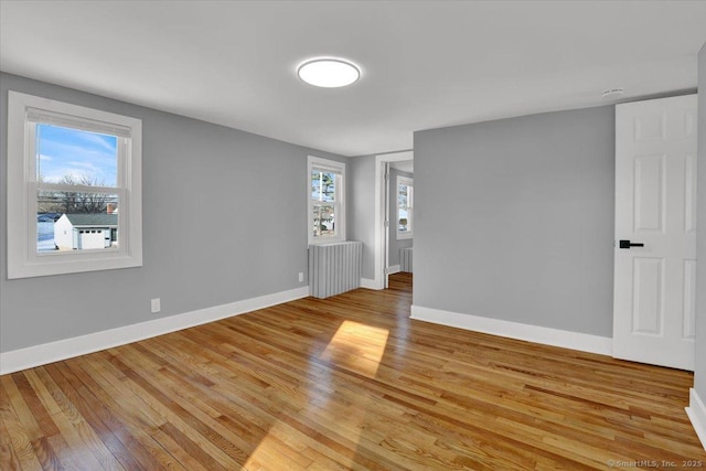 empty room with radiator heating unit and light hardwood / wood-style floors