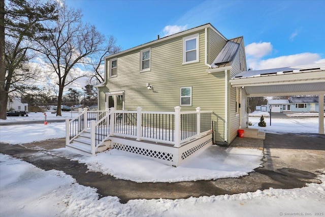 snow covered house with a wooden deck