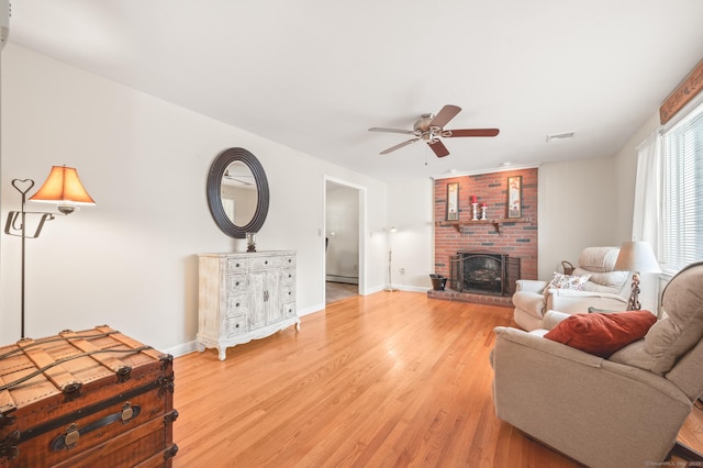 living room featuring ceiling fan, wood-type flooring, and a fireplace