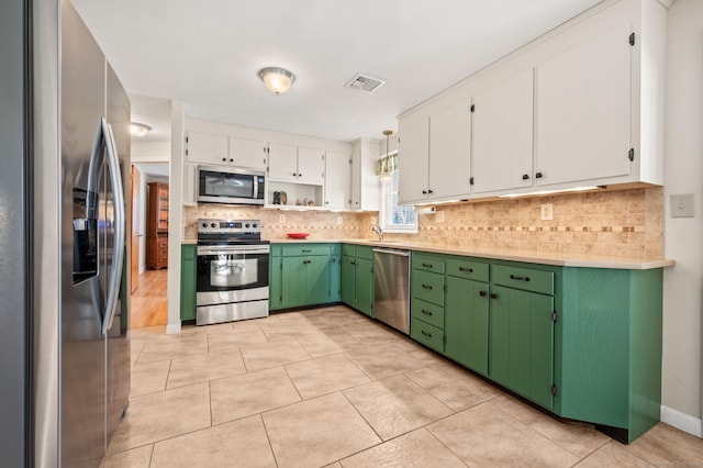 kitchen with pendant lighting, stainless steel appliances, green cabinetry, and white cabinets