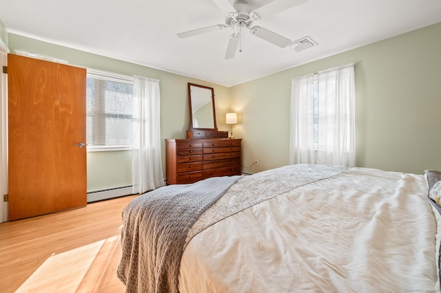 bedroom with ceiling fan, light wood-type flooring, and baseboard heating