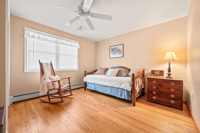 bedroom featuring ceiling fan, a baseboard heating unit, and light wood-type flooring