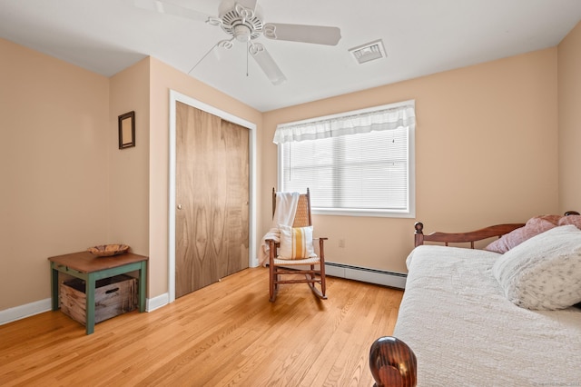 bedroom featuring light hardwood / wood-style floors, a closet, ceiling fan, and baseboard heating