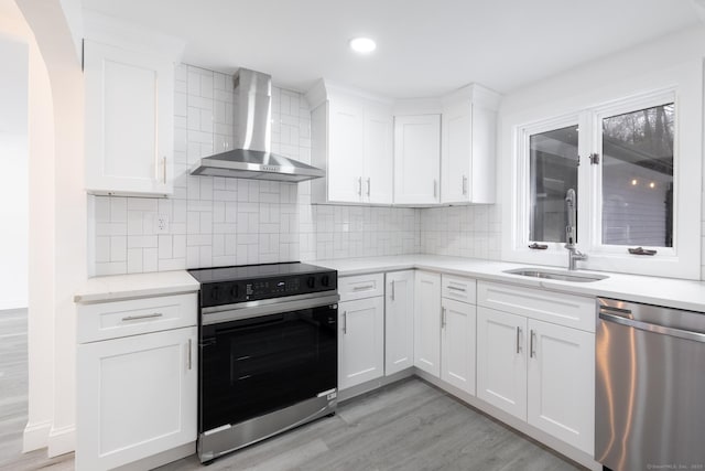 kitchen featuring white cabinetry, electric range, stainless steel dishwasher, and wall chimney exhaust hood