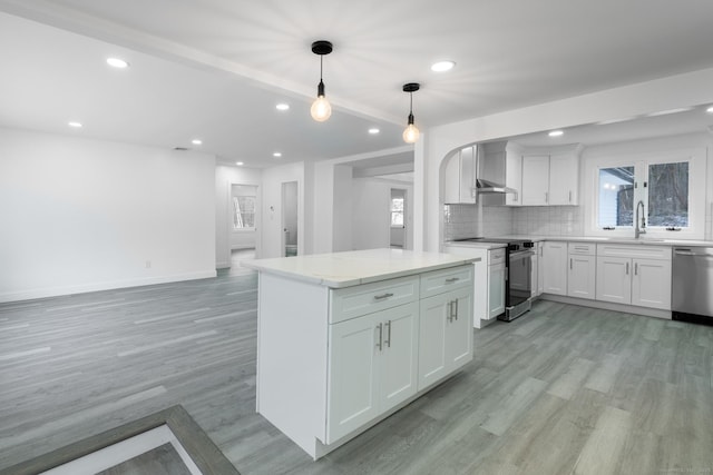 kitchen featuring appliances with stainless steel finishes, white cabinetry, decorative backsplash, decorative light fixtures, and light wood-type flooring