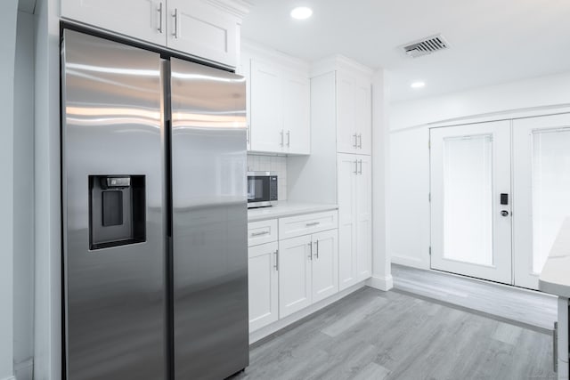 kitchen featuring backsplash, stainless steel appliances, white cabinets, french doors, and light wood-type flooring