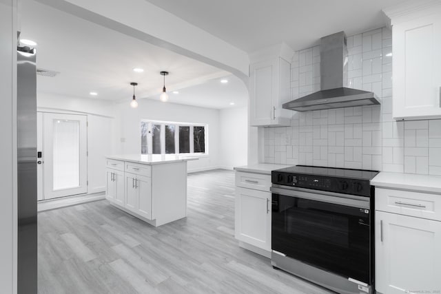 kitchen featuring decorative light fixtures, range with electric stovetop, white cabinets, wall chimney range hood, and backsplash