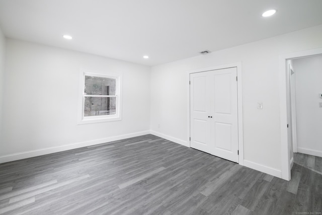 unfurnished bedroom with dark wood-type flooring and a closet