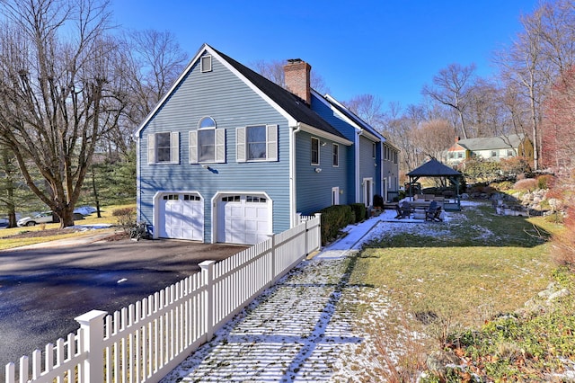 view of property exterior featuring a garage and a gazebo