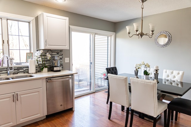 kitchen with pendant lighting, white cabinetry, sink, decorative backsplash, and stainless steel dishwasher