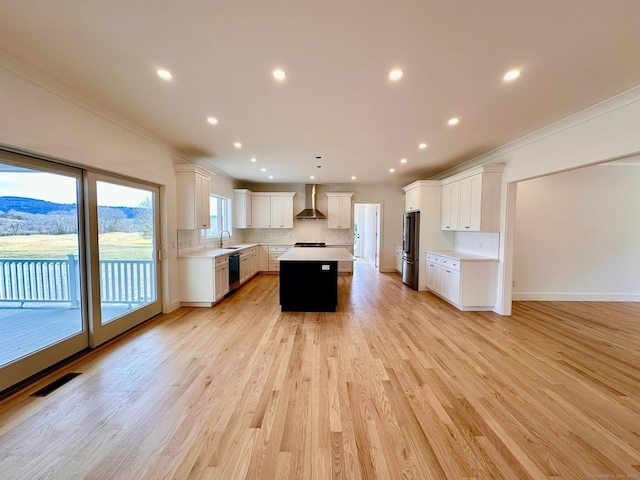 kitchen with wall chimney exhaust hood, white cabinetry, stainless steel fridge, black dishwasher, and a kitchen island