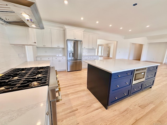 kitchen featuring white cabinetry, stainless steel appliances, exhaust hood, and a kitchen island