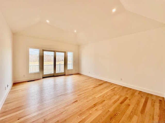 spare room with lofted ceiling and light wood-type flooring