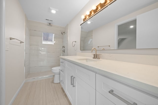 bathroom with vanity, tiled shower, and toilet