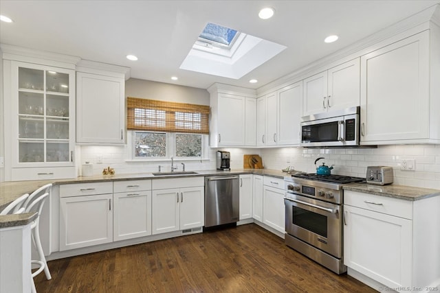 kitchen with sink, stainless steel appliances, dark hardwood / wood-style floors, light stone countertops, and white cabinets