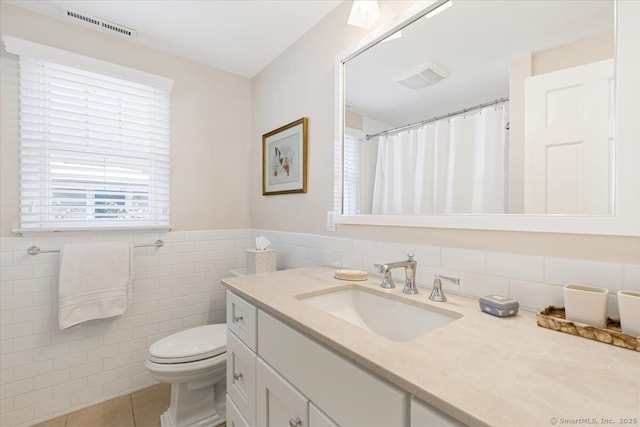 bathroom with tile patterned flooring, vanity, tile walls, and toilet