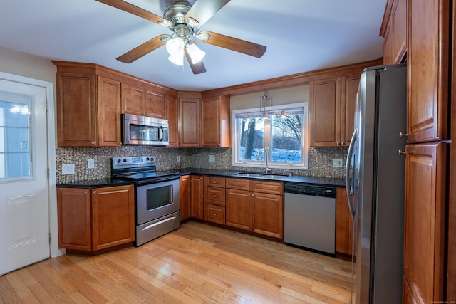 kitchen with sink, ceiling fan, stainless steel appliances, tasteful backsplash, and light hardwood / wood-style floors